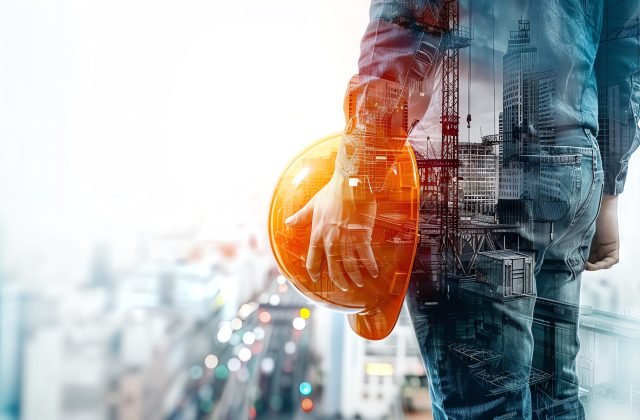 A construction worker holding a hard hat in front of a city skyline. The image is a double exposure, with the worker's form partially transparent.